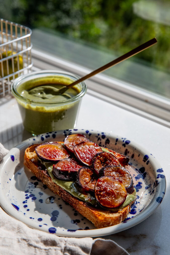 Plate of toast with pumpkin seed butter and figs on top with a jar of pumpkin seed butter in the background.