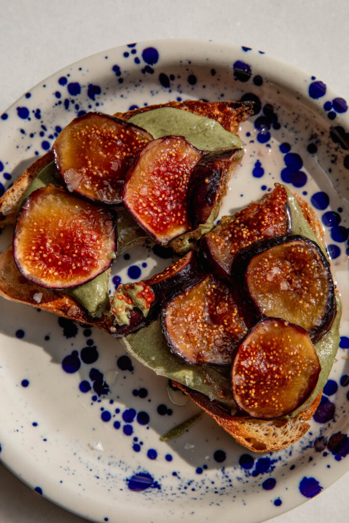 Toast with pumpkin seed butter and figs cut in half on a plate.