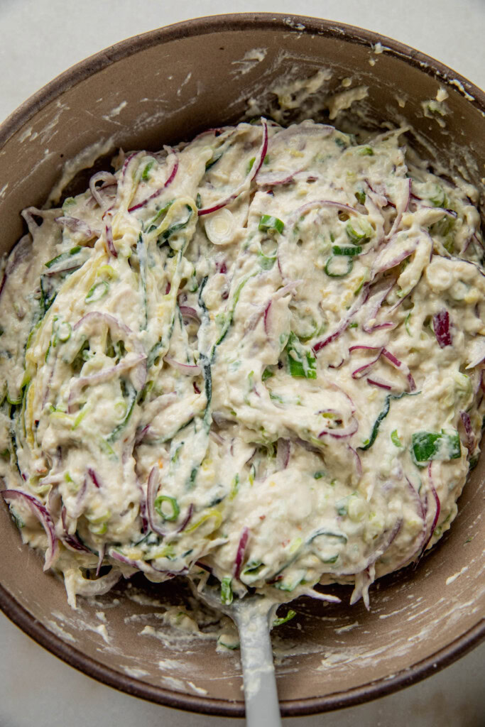 Mixed vegetable batter spread out in a pan with oil.