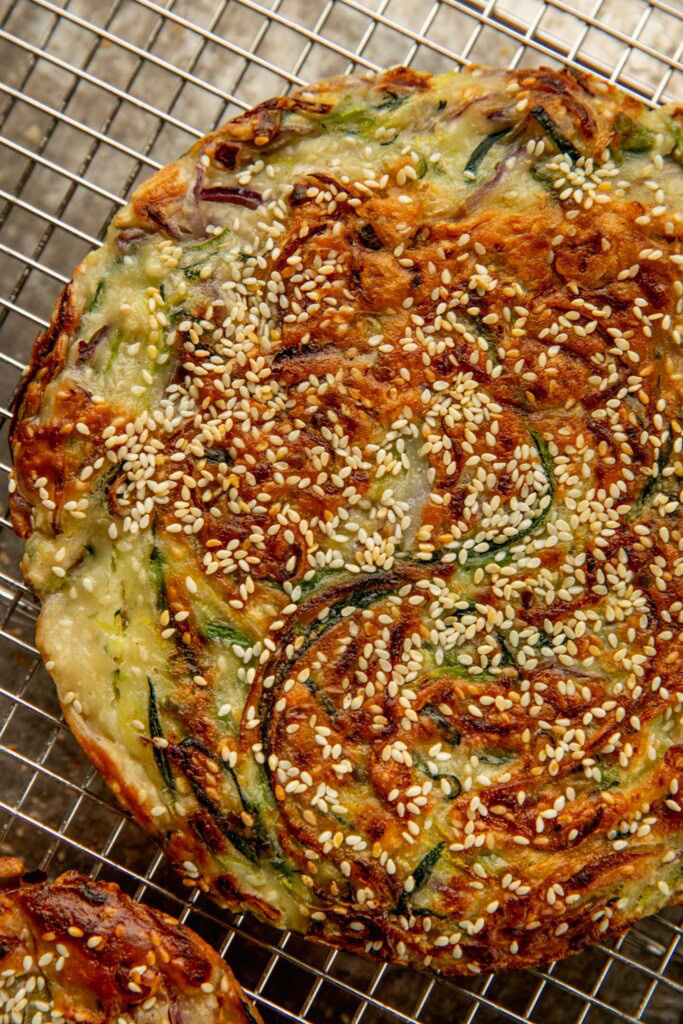 A fully cooked zucchini pancake placed on a cooling rack.