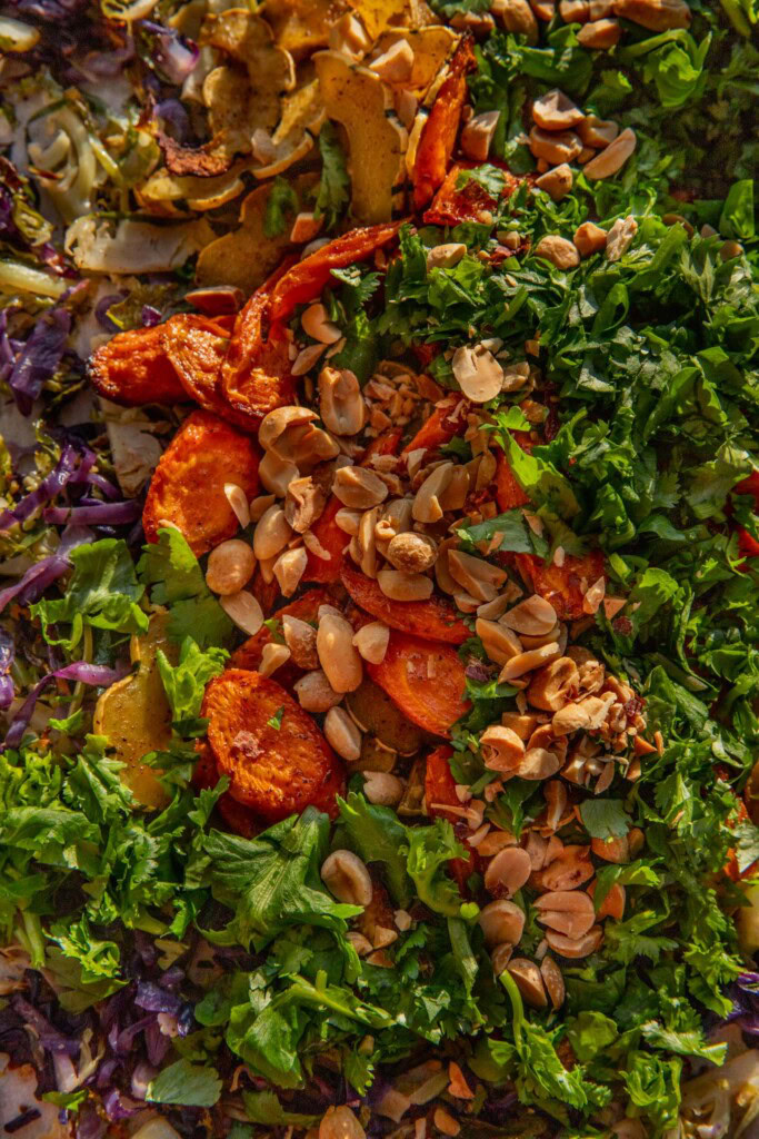 Combining the roasted veggies all on one sheet pan with peanuts, cilantro, scallions, and peanut sauce.