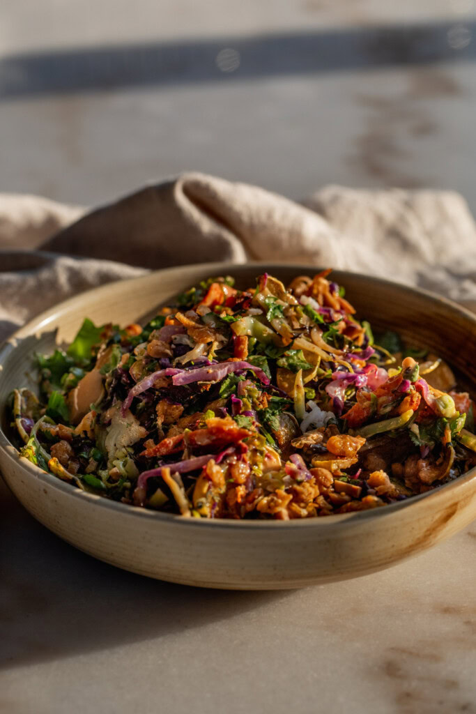 Bowl of roasted carrot salad topped with chickpeas and peanut hoisin sauce.