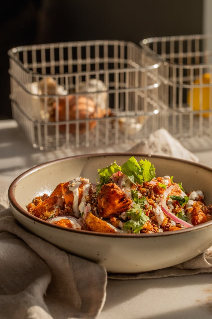 Far away shot of a bowl piled high with roasted potatoes, crumbled tofu and garlic sauce.